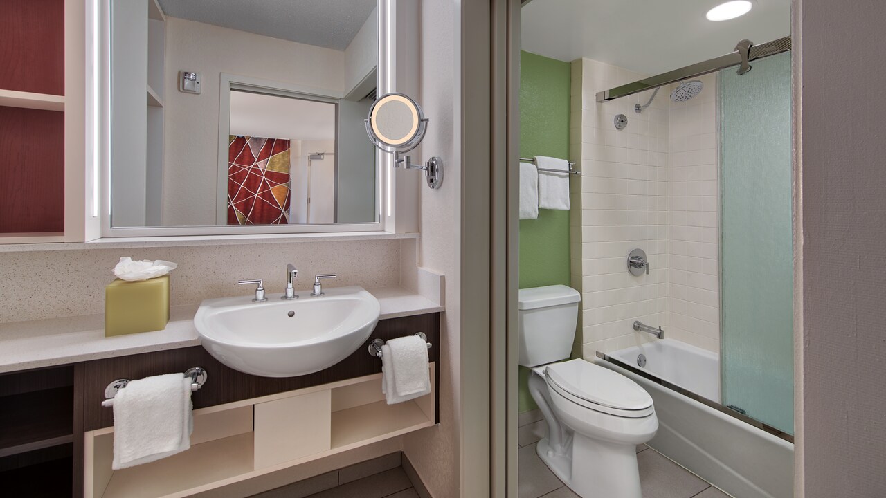 Bathroom sink, mirror, towels, toilet next to tub