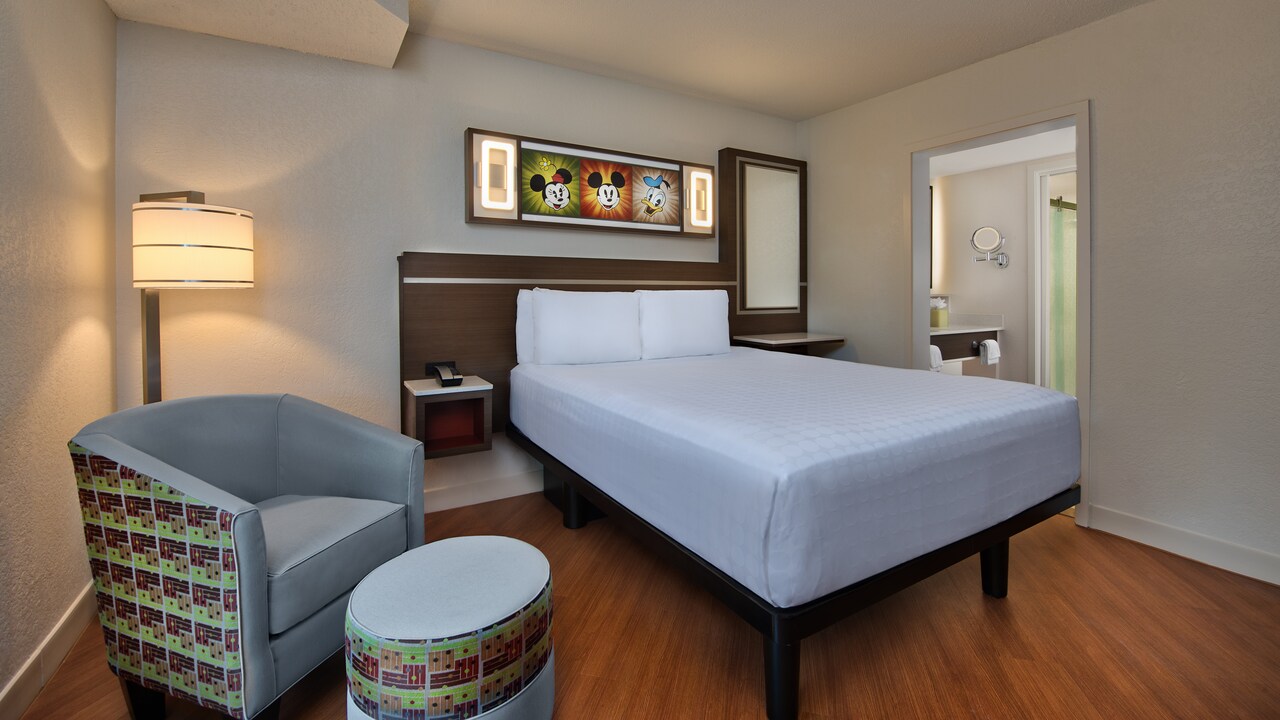 Chair, ottoman, floor lamp, bed, end tables, mirror and Disney character artwork above bed on wall