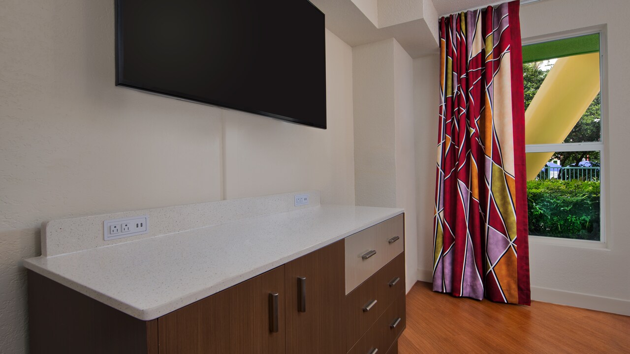 TV on wall above dresser, curtain next to window