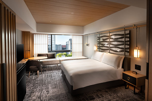King deluxe city-view room with a white bed and Kyoto buildings beyond the open shoji