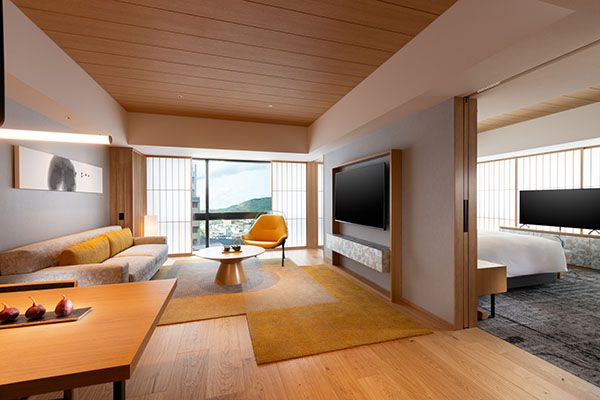 King Deluxe Suite living room with a sofa, a yellow chair, and the bedroom through a sliding door
