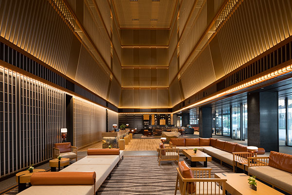 Hilton Kyoto lobby with a high wood-slat ceiling, leather sofas, and a long patterned carpet