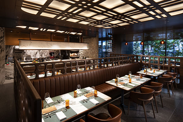Seven Embers restaurant with brown banquettes, marble tables, and an open kitchen