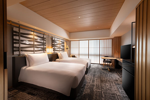 Twin guest room with two white beds, shoji screens, and a desk by the window