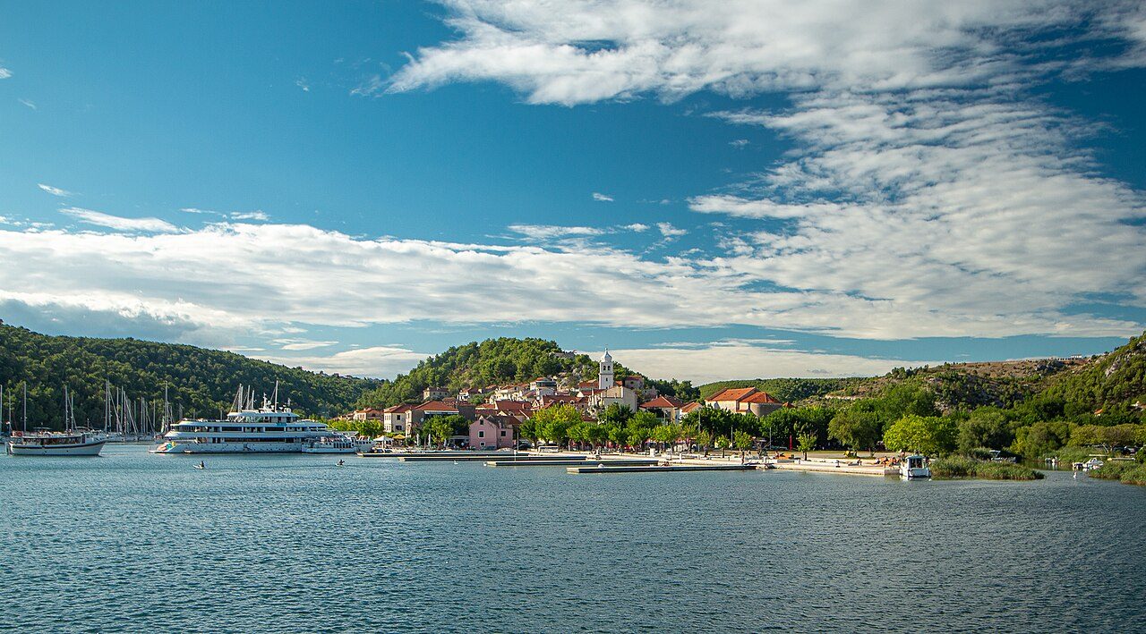 Skradin harbor, with a passenger boat, sailboats, and the bell tower on the hill