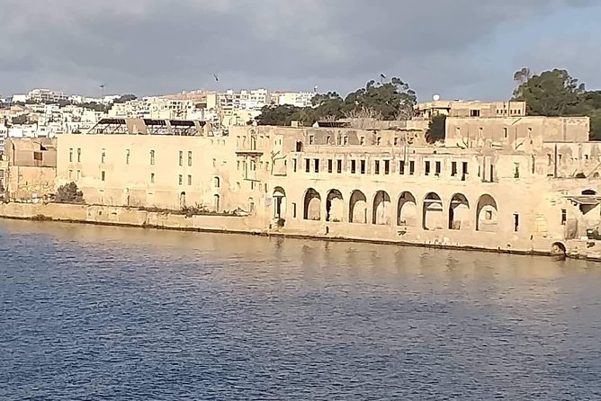 Limestone waterfront building with arched openings along a Malta harbor