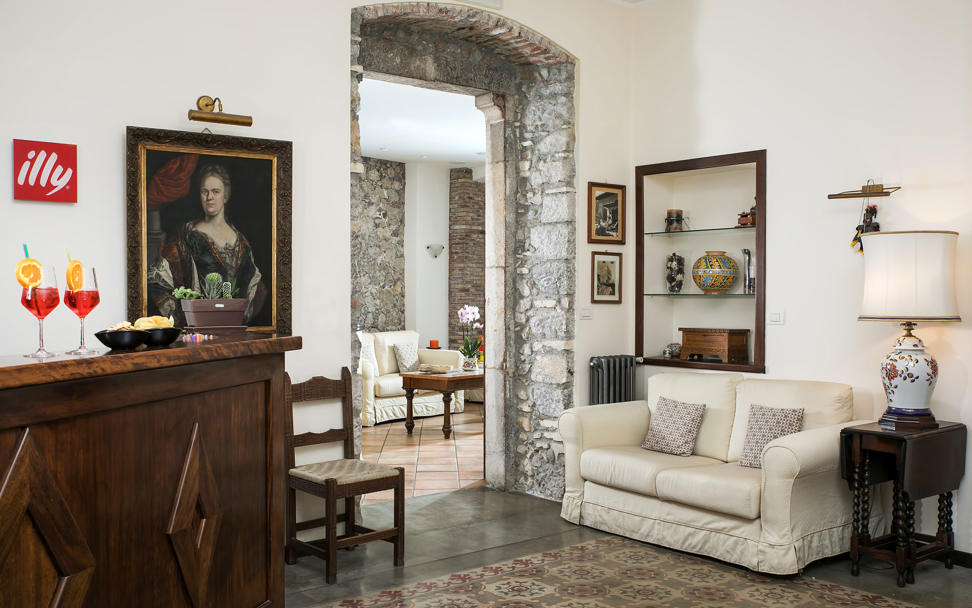 Hotel lounge with a sofa, a stone arch, and a wooden bar