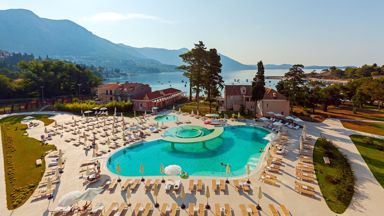 Outdoor pool and sun loungers at Sheraton Dubrovnik Riviera, with the bay and mountains beyond