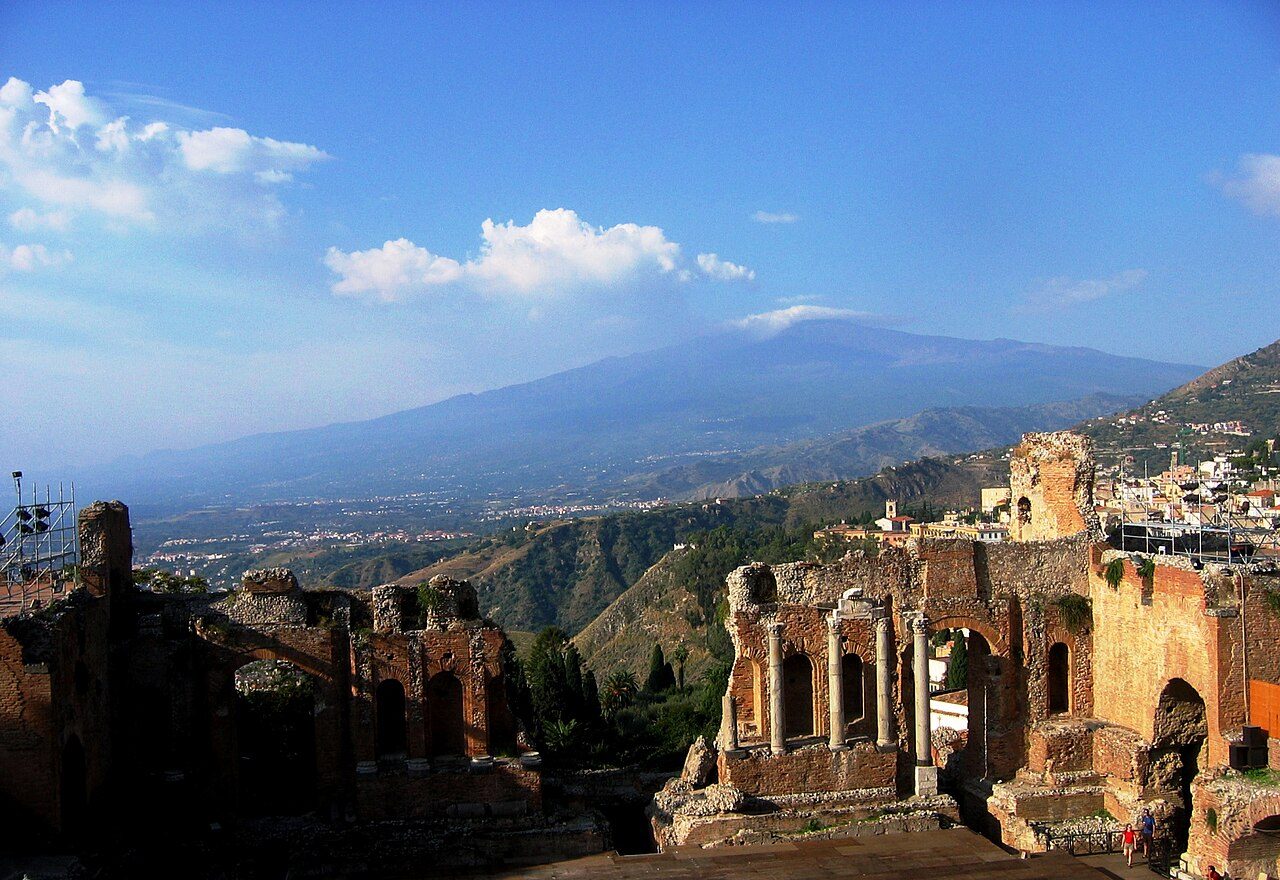 Brick stage wall and columns of the Ancient Theatre, with Mount Etna across the bay