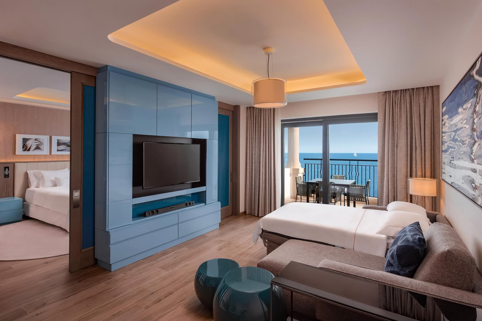Luxury Bay Suite living room with a sofa bed, a bedroom beyond, and a balcony over the sea