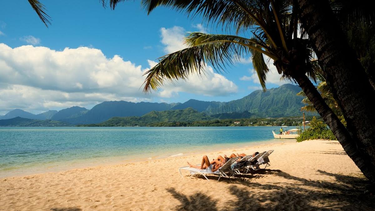 Lounge chairs on the private beach at Kualoa Ranch Secret Island, looking across Kaneohe Bay to the Koʻolau mountains