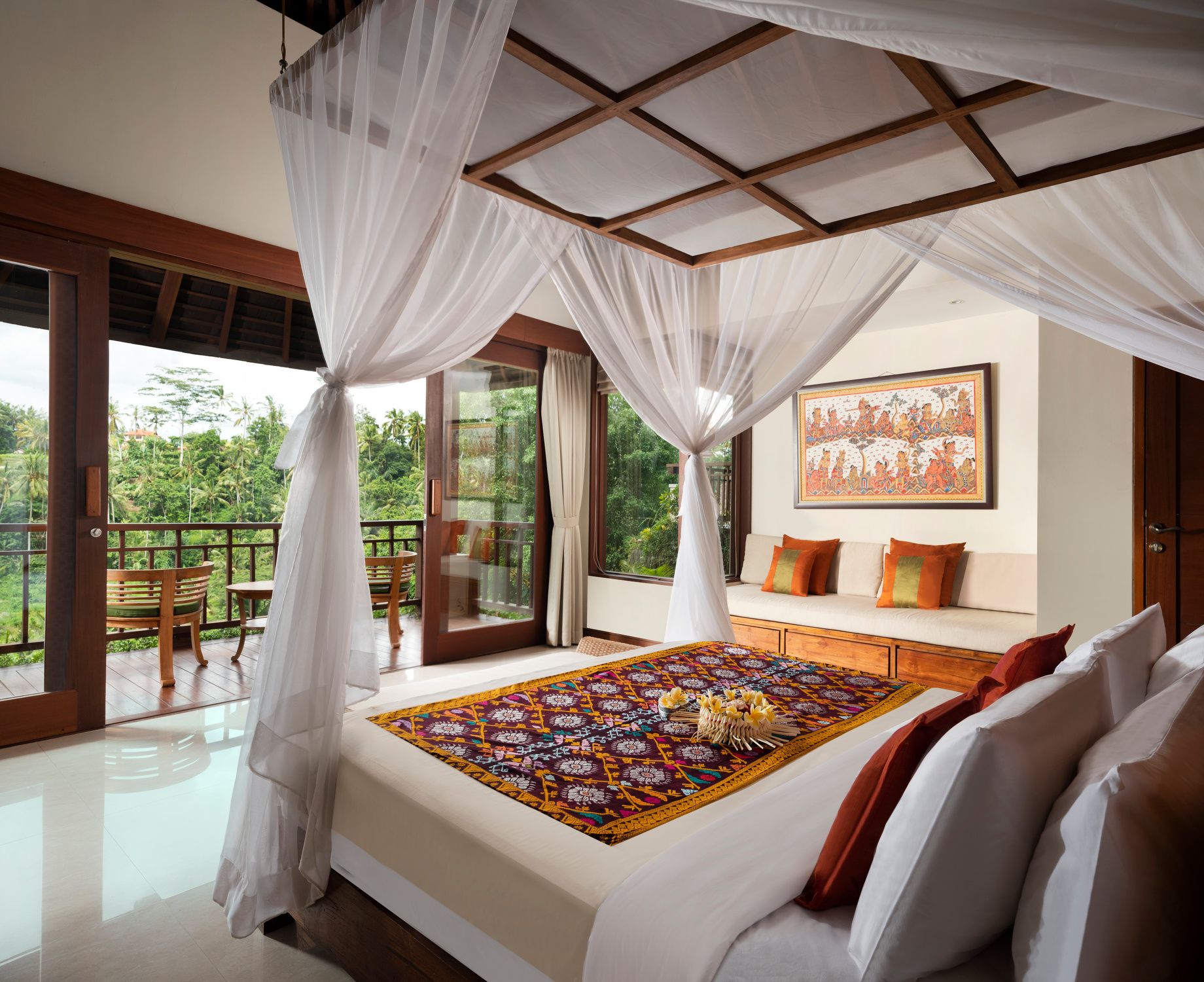 Deluxe Suite bedroom with a daybed and sliding doors to the jungle balcony at Jannata Ubud
