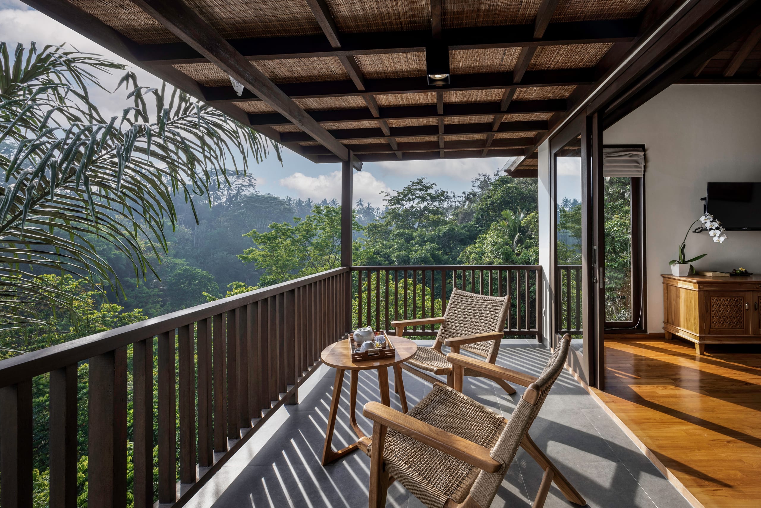 Covered balcony with two chairs looking over the jungle at Jannata Resort Ubud